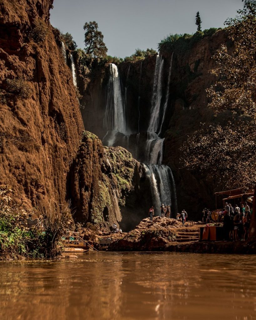 people standing on brown rock formation near waterfalls during daytime
